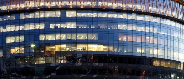 Modern office building with big windows at night, in windows light shines.Moscow, Russia