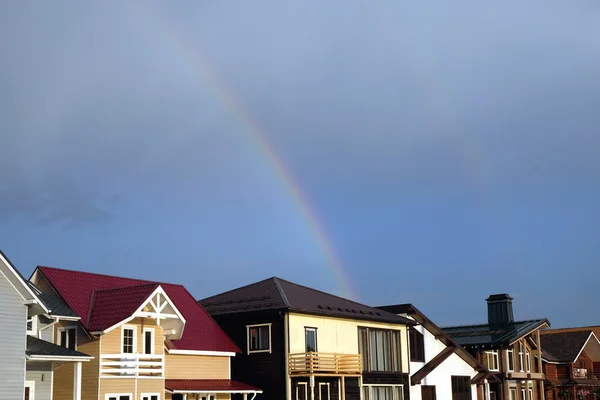 Landscape with rainbow after rain above cottage village homes