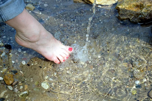 Female bare feet under rinning water closeup