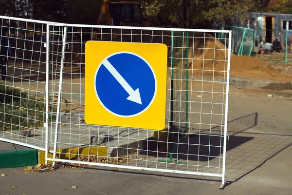 Repair work. Road sign indicating detour hanging on fence