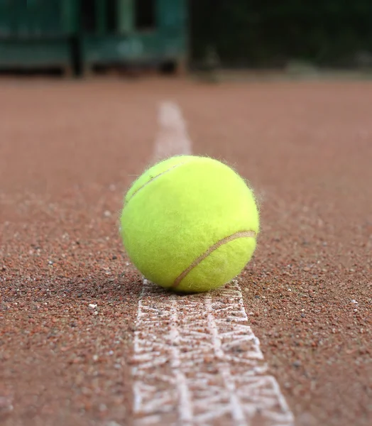 Yellow tennis ball lays on ground court closeup