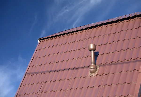 Roof of a house covered with metal tile with chimney
