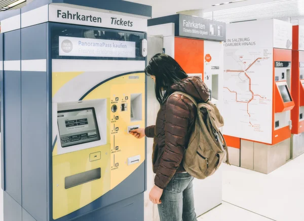 Traveling by train at the Alpine Railroad. She buys a train ticket at the ticket machine at the train station