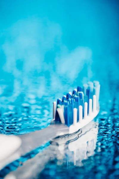 Toothbrush on blue background with water drops
