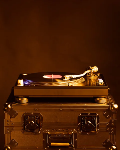 Professional dj turntable on flight case, dark background, golden tone