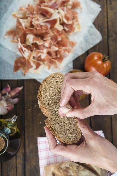 Chef rubbing garlic on a bread slice