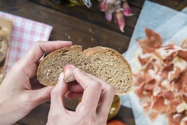 Chef rubbing garlic on a bread slice