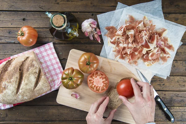 Chef rubbing tomato on a slice of bread