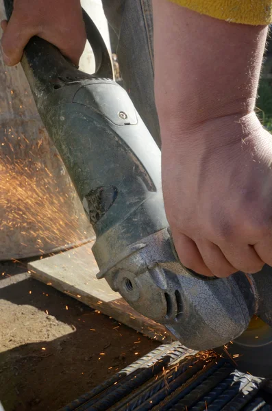 Worker cutting metal with grinder withs parks while grinding iron