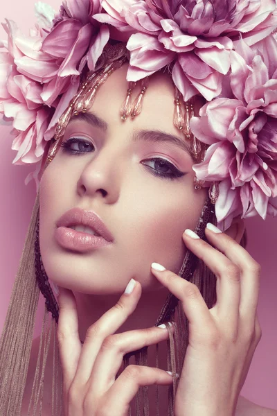 Beautiful woman with flower crown and makeup on pink background