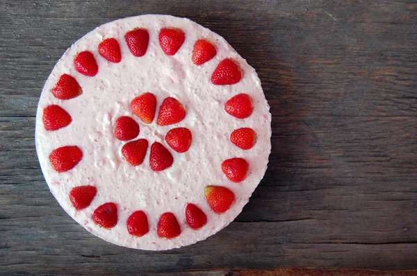 Background with raw strawberry cake on rustic wooden table