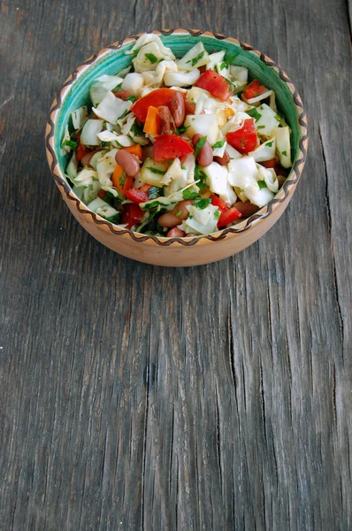 Fresh tomato and cabbage salad with parsley in ceramic bowl on rustic wooden table