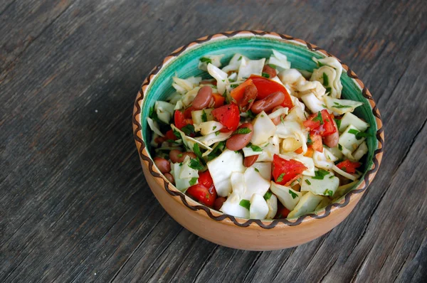 Fresh tomato and cabbage salad with parsley in ceramic bowl on rustic wooden table