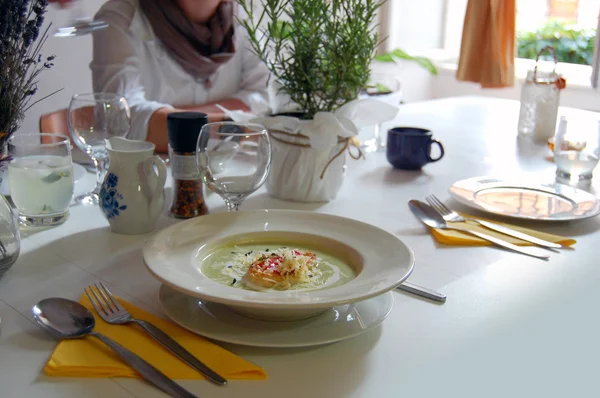 Detail of dinner table with green pea soup