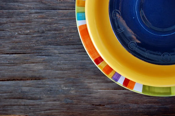 Colorful plates on wooden background