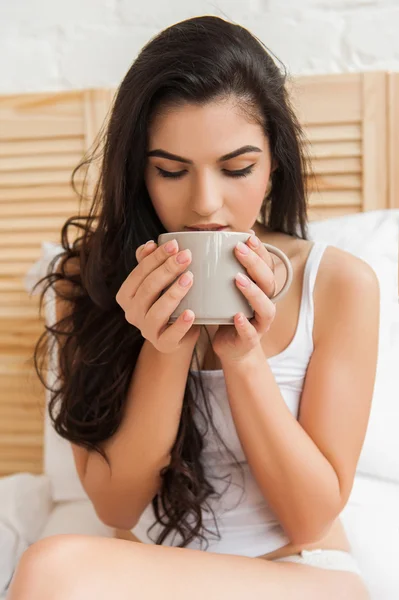 Cute young beautiful woman drinking tea in the bed