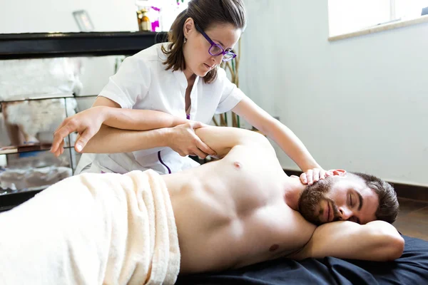 Masseur doing massage on man body in the spa salon.