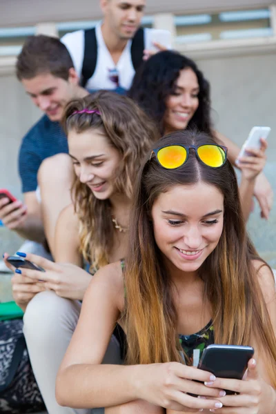 A group of students having fun with smartphones after class.
