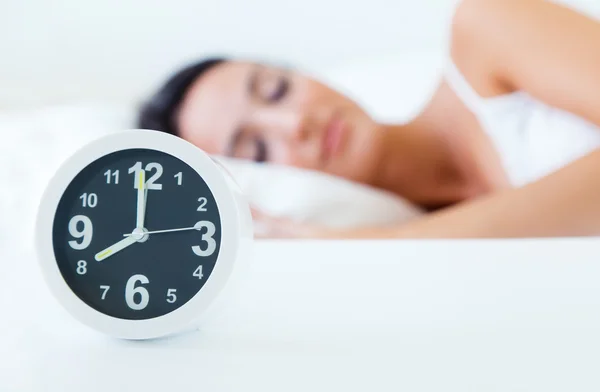 Beautiful woman sleeping in bed trying to wake up with alarm clock.