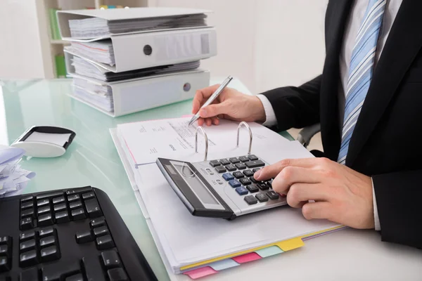 Businessman Calculating Invoice With Calculator