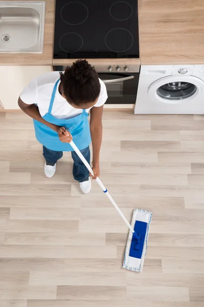 Female Janitor Cleaning Floor In Kitchen