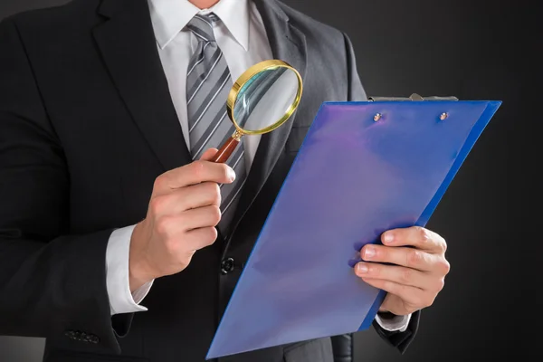 Businessman Examining Document On Clipboard