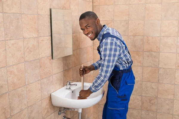 Plumber Using Plunger In Bathroom Sink