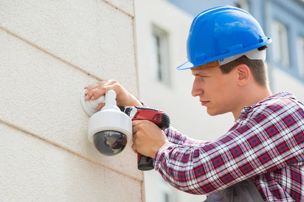 Young Male Technician Installing Camera On Wall