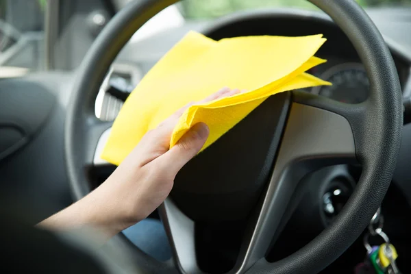 Man Cleaning Steering Wheel Of Car With Cloth