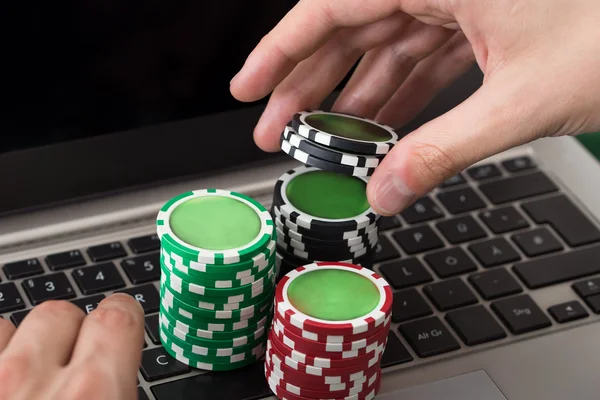 Businessman Using Laptop With Stacked Poker Chips