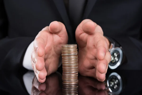 Businessman Protecting Stacked Coins
