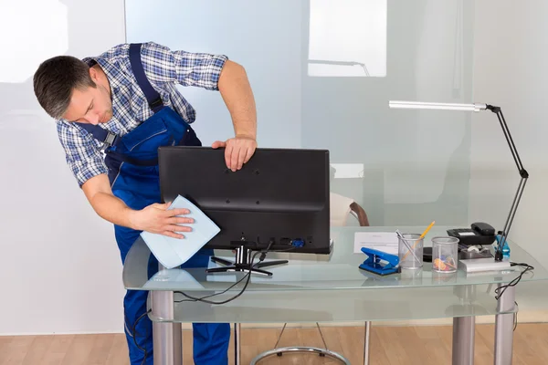 Male Janitor Cleaning Computer In Office