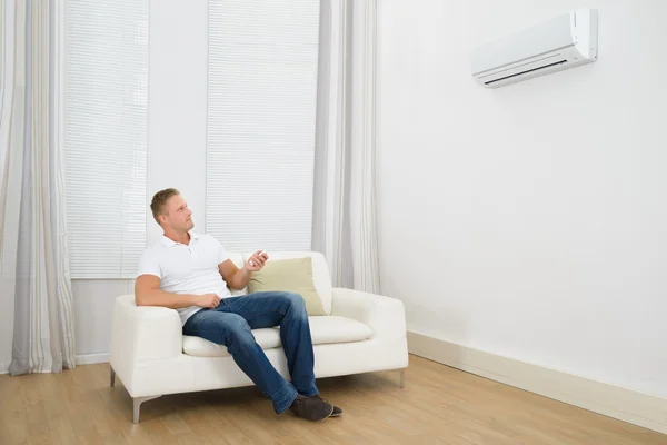 Man Adjusting Temperature Of Air Conditioner