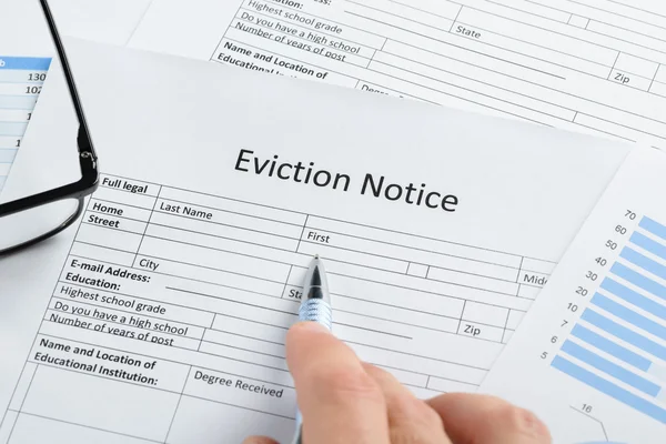 Hand With Pen Over Eviction Notice
