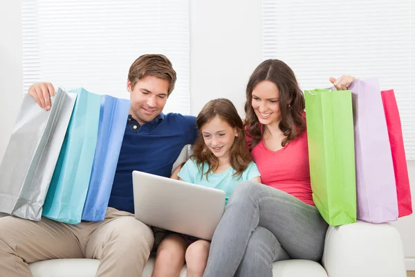 Family With Shopping Bags Using Laptop