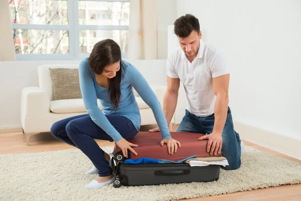Couple Trying To Close Suitcase