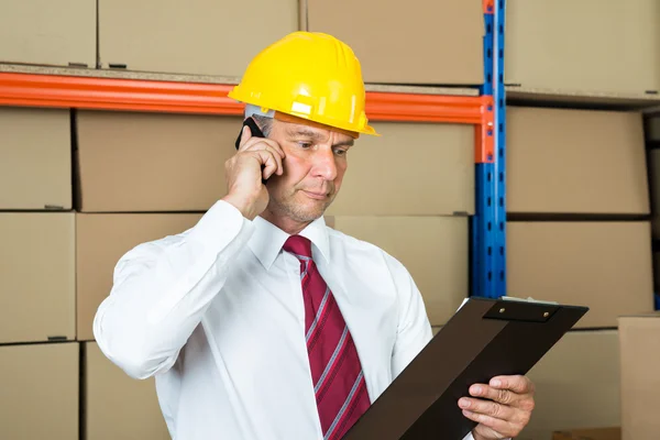 Businessman With Clipboard Using Mobile Phone
