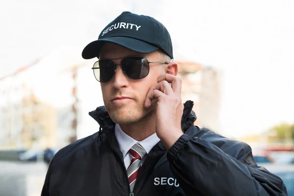 Security Guard Listening To Earpiece