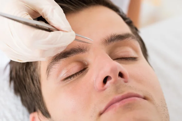 Beautician Hands Plucking Man Eyebrows With Tweezers