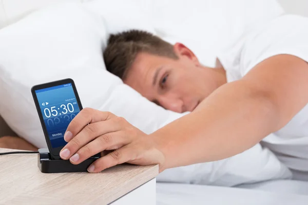 Man Snoozing Alarm Clock On Cell Phone