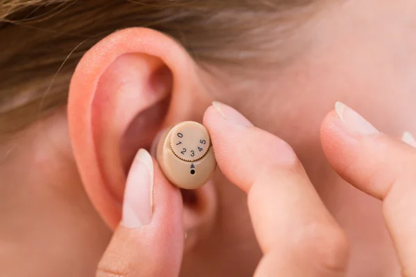 Hands Putting Hearing Aid In Ear
