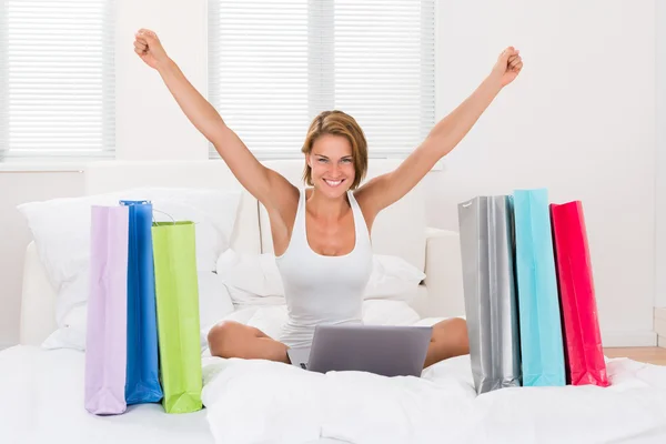 Woman With Shopping Bags And Laptop In Bed