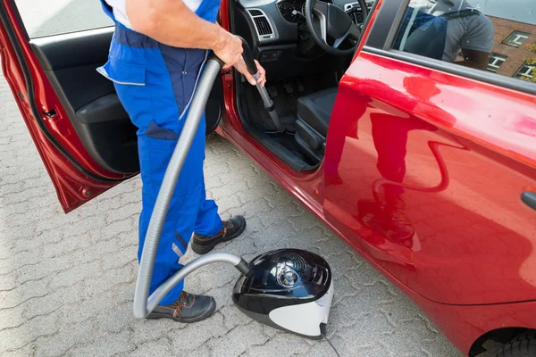 Worker Vacuuming Car With Vacuum Cleaner