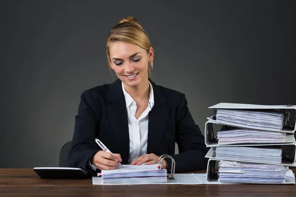 Businesswoman Writing On Document At Desk