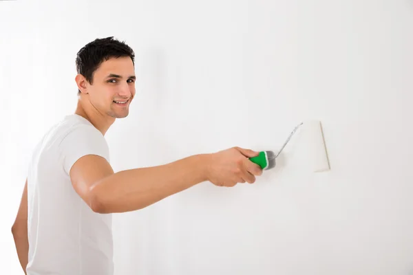 Man Using Paint Roller On Wall