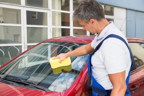 Worker Cleaning Car Windshield With Sponge
