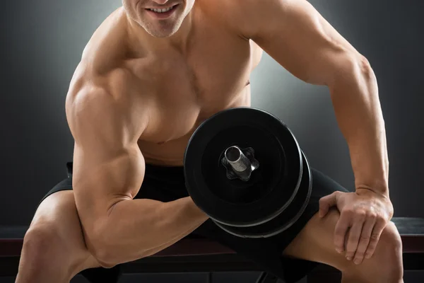 Man Lifting Dumbbell While Sitting On Chair