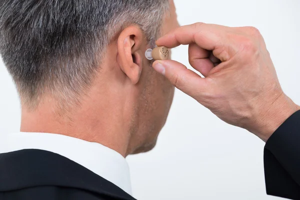 Businessman Inserting Hearing Aid