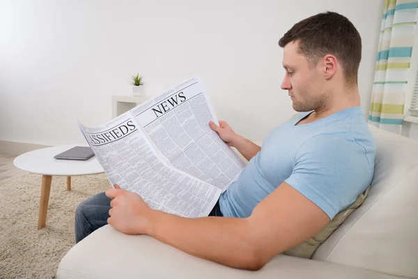 Man Reading Newspaper At Home
