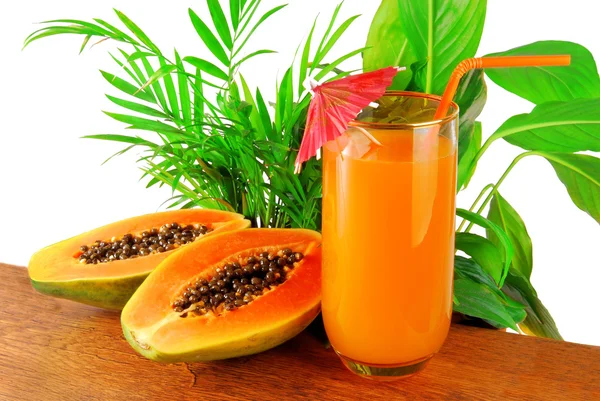 Papaya fruit and glass of juice and exotic leaves